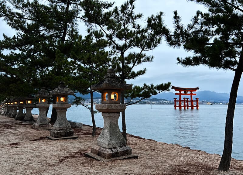 Promenez-vous avec des lanternes en pierre à côté du torii au coucher du soleil
