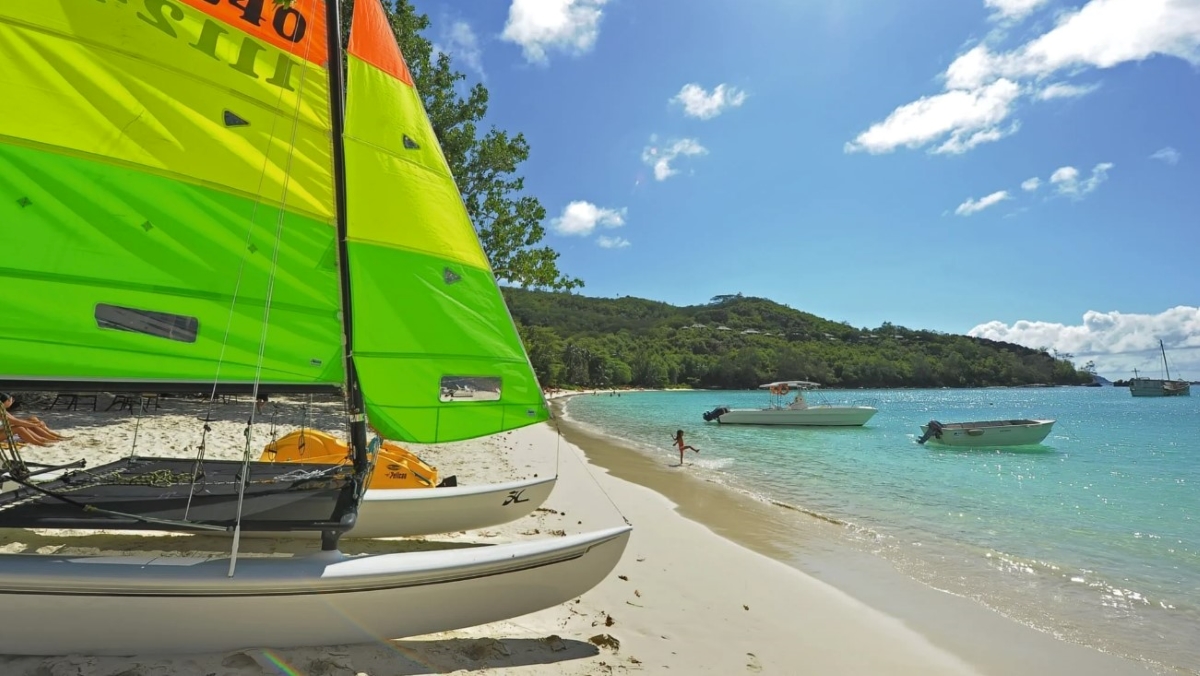 Plage avec enfants jouant dans les vagues, bateau au premier plan et en arrière-plan