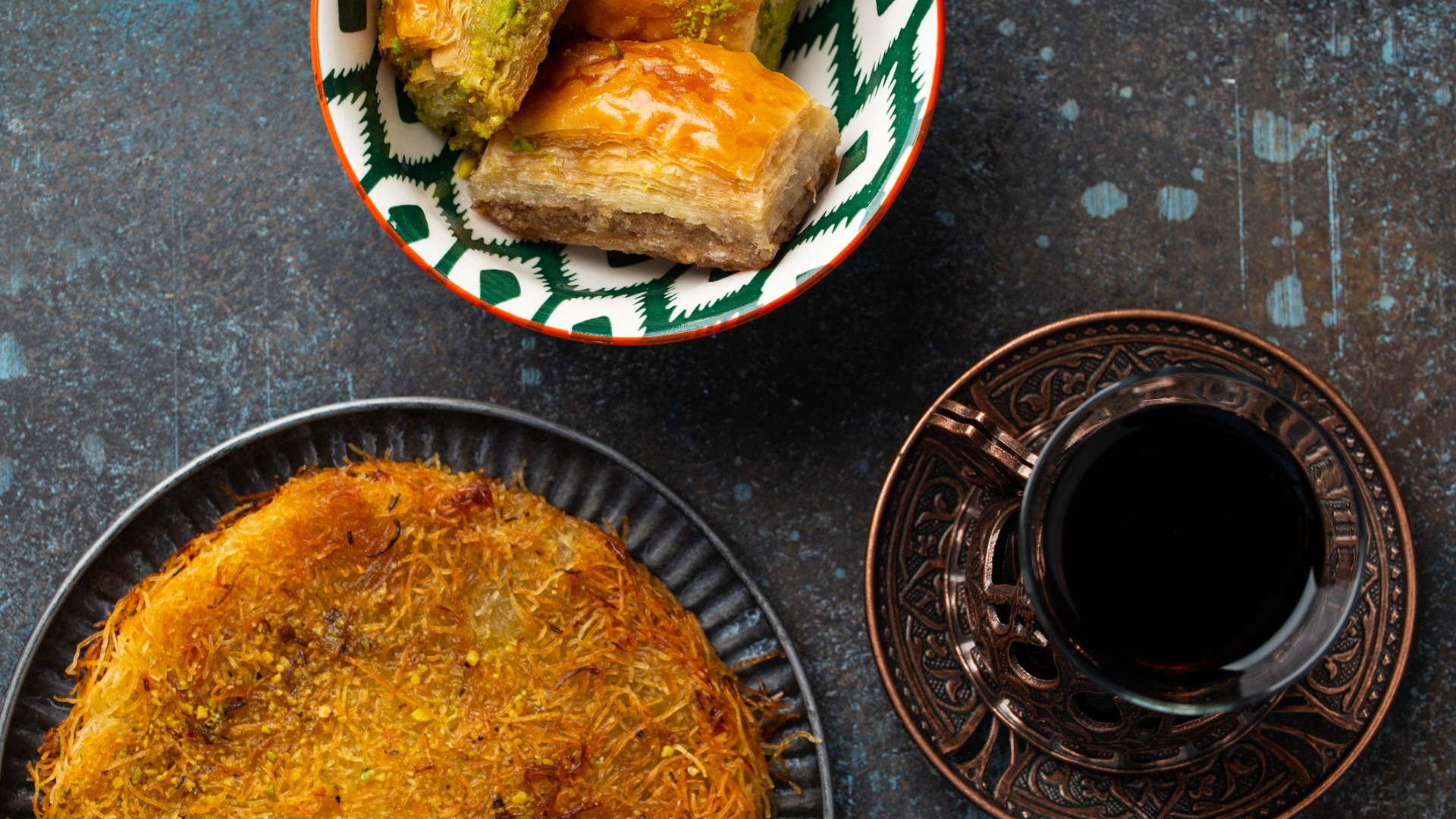 Il s'agit d'une photo supérieure qui montre un dessert Kunefe, un peu de baklava et une tasse de thé turc traditionnel.