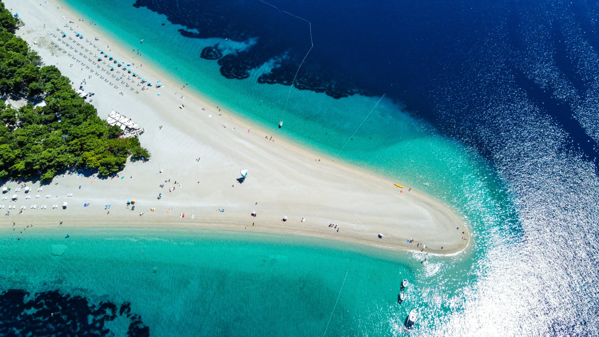 Il s'agit d'une photo prise par drone de haut en bas de la plage de Zlatni Rat. Il y a une terre étroite de sable blanc et d’eau turquoise folle. 