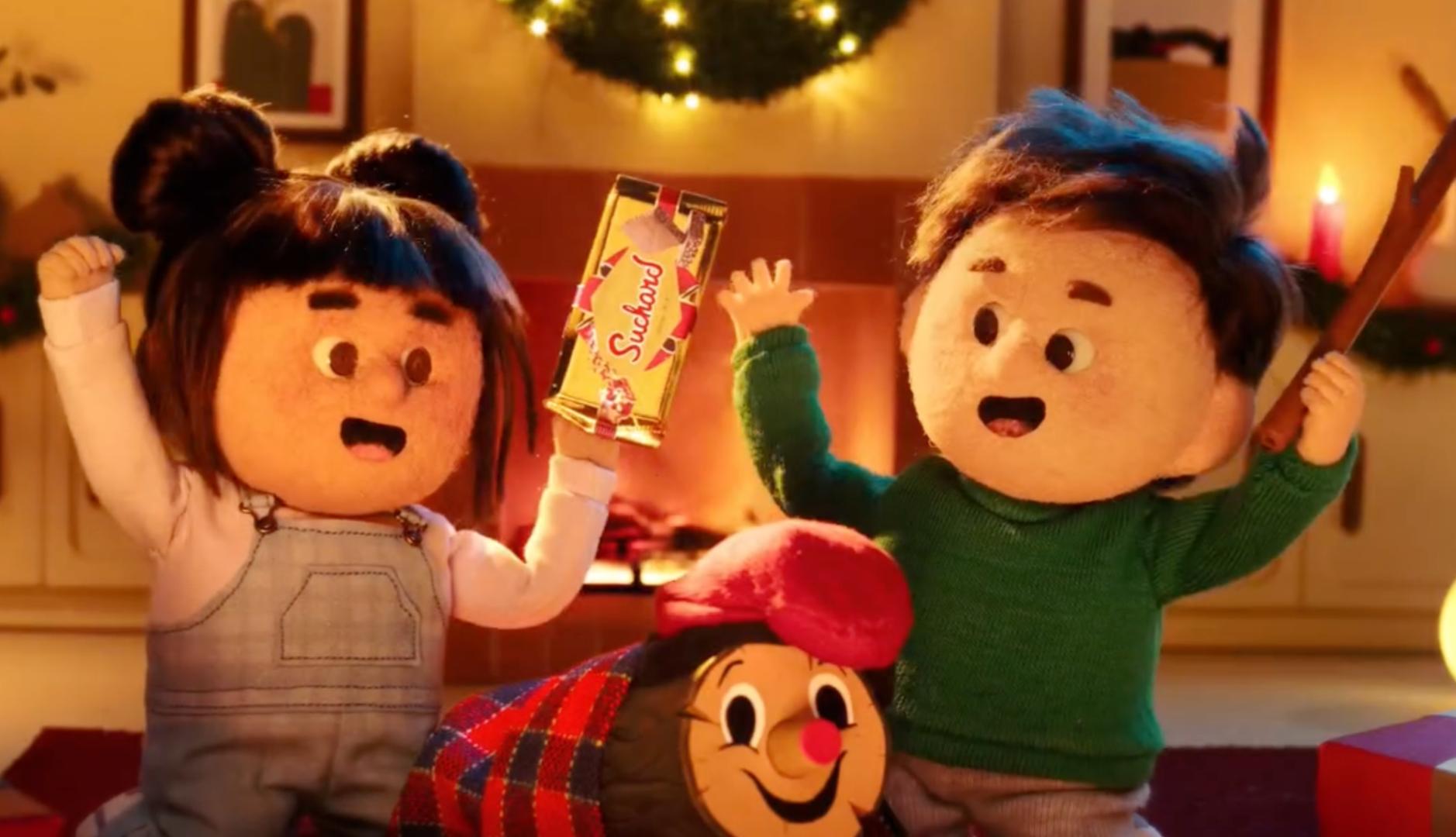 Dos niños celebrando la Navidad con una tableta de Suchard en la mano