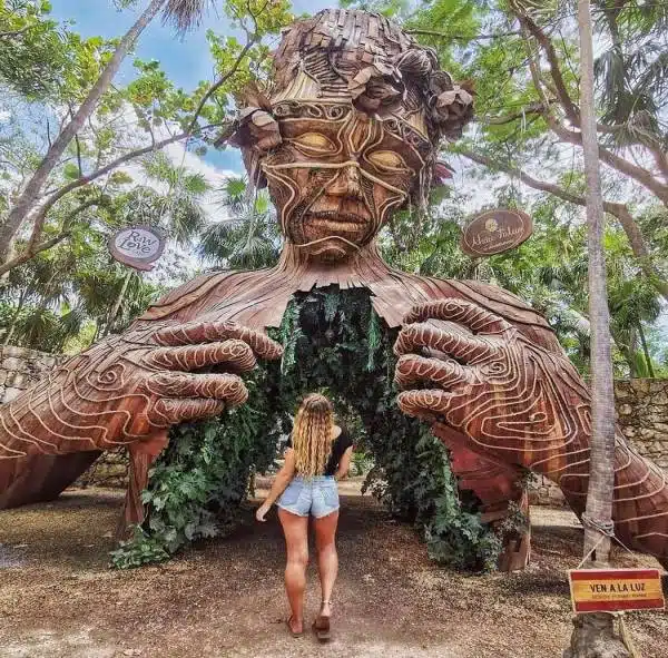 Tulum-femme devant une statue