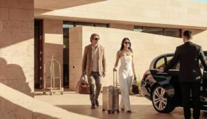 Una pareja saliendo de su casa mientras el chófer les espera abriendo la puerta del coche