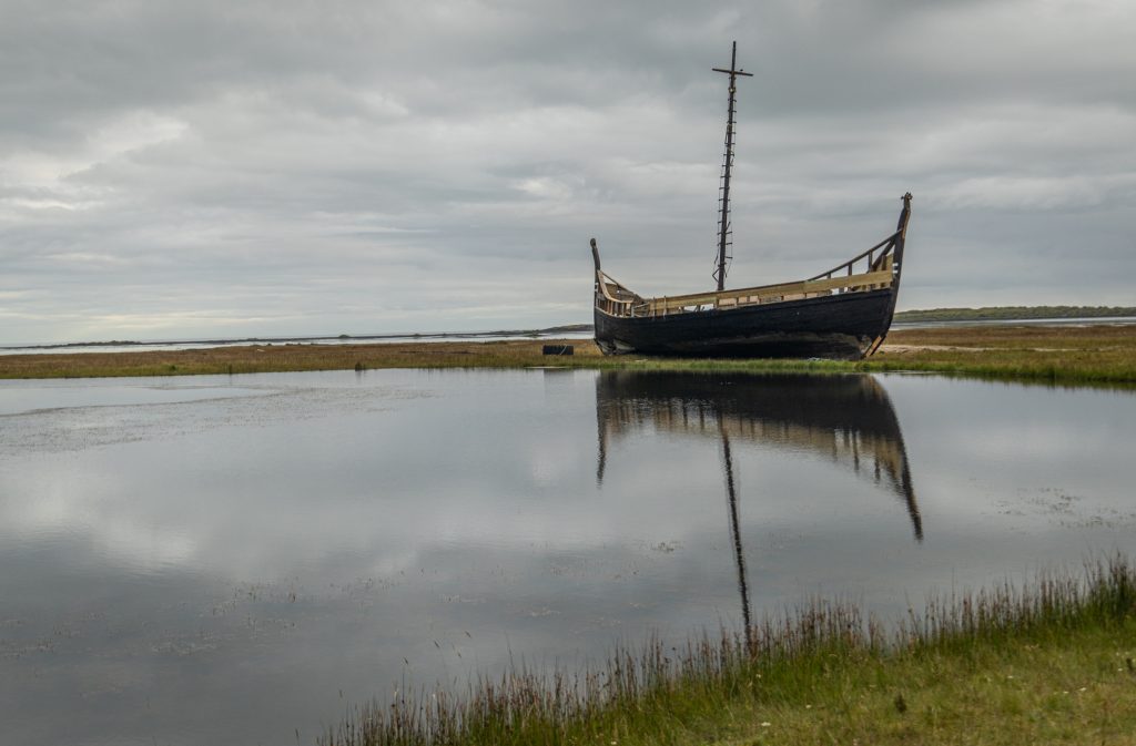 Un bateau viking est amarré dans des eaux calmes avec un reflet parfait.