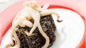 Este es un primer plano de un plato de risotto negro cubierto con sepia. Este risotto croata es el más famoso del país.
