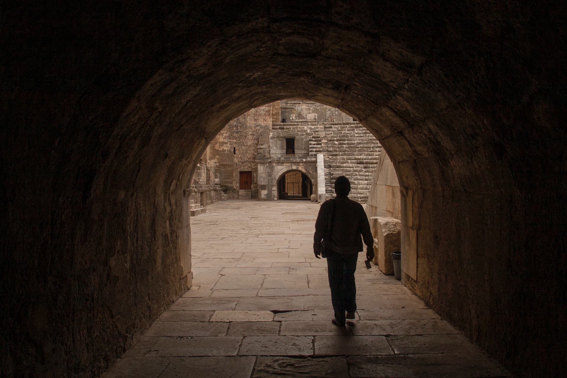Cette image montre un homme marchant sous le passage voûté du théâtre Aspendos.